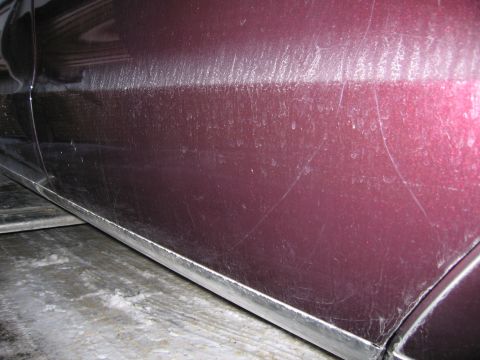1991 Ford LTD Crown Victoria - Close-up photo of a maroon car door and rocker panel showing light scratches and surface wear.
