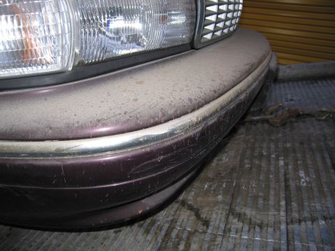 1991 Ford LTD Crown Victoria - Photograph of a car's front bumper, grille and headlight, not a technical document.