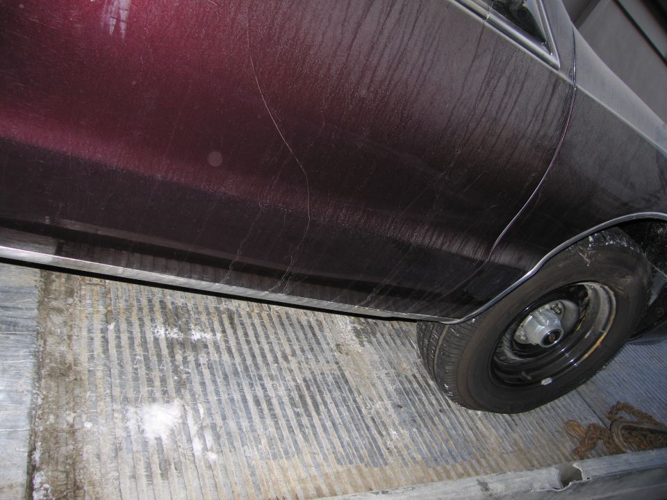 Photo of a maroon car's lower body side and rear wheel