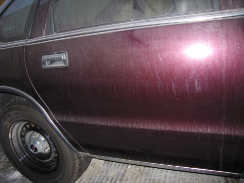 1991 Ford LTD Crown Victoria - Photograph of a car door, handle and steel wheel, not a technical document.