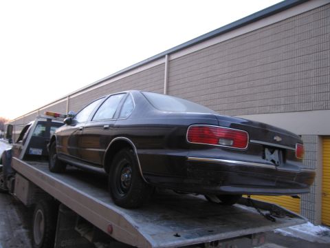 1991 Ford LTD Crown Victoria - Photograph of a Chevrolet sedan on a flatbed tow truck, not a technical document.