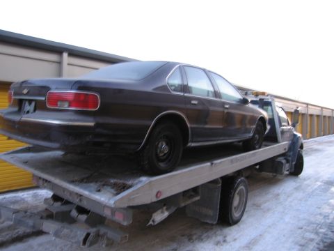 1991 Ford LTD Crown Victoria - Photograph of a Chevrolet sedan on a flatbed tow truck, not a technical document.