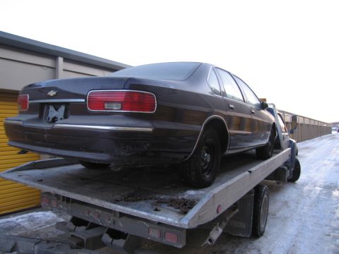 1991 Ford LTD Crown Victoria - Photograph of a Chevrolet sedan on a flatbed tow truck, not a technical document.