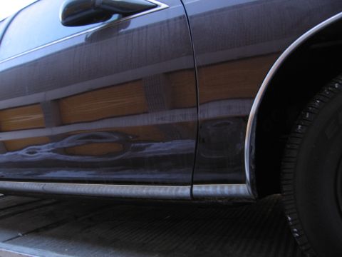 1991 Ford LTD Crown Victoria - Photograph of a vehicle's woodgrain side trim and rear wheel, not a technical document.