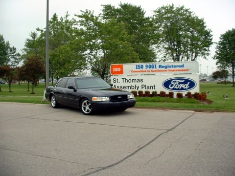 2000 Ford Crown Victoria - A dark-colored Ford Crown Victoria is parked in front of the St. Thomas Assembly Plant, which is ISO 9001 Registered.