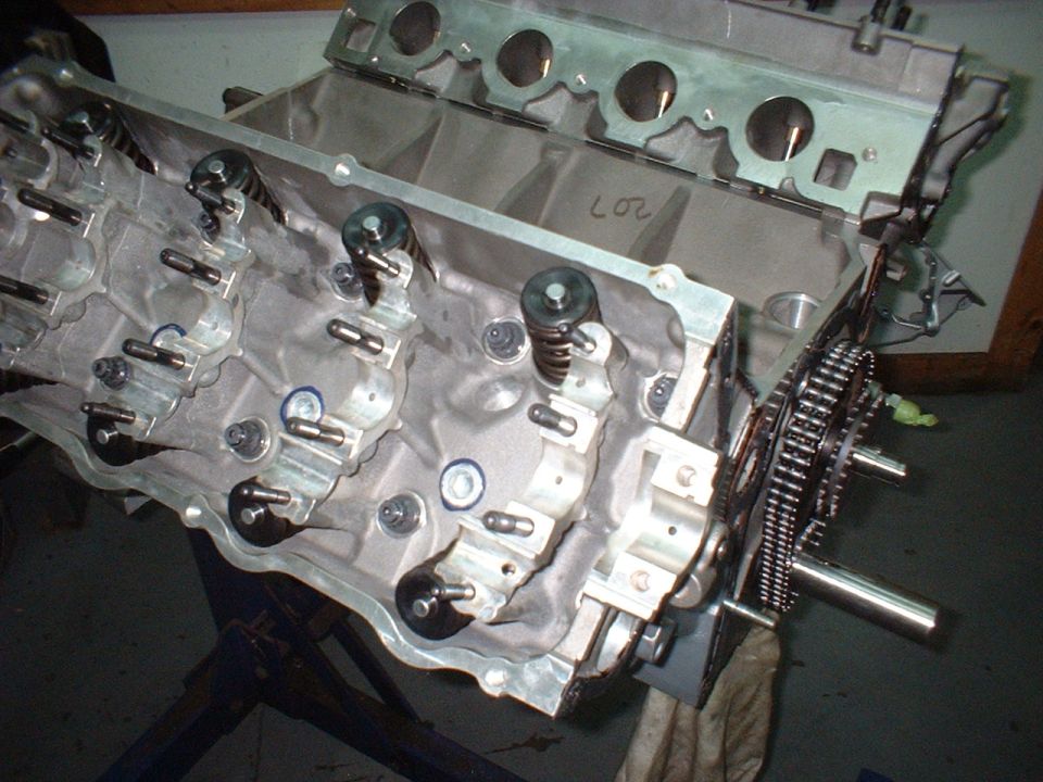 Engine block with rocker arms, valve springs, and timing chain visible.