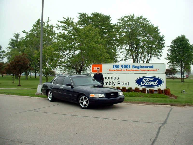Dark blue Crown Victoria in front of the St. Thomas Assembly Plant Ford sign
