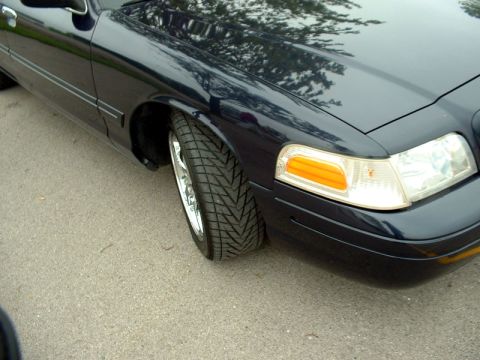 2000 Ford Crown Victoria - Front corner view of a dark blue 2000 Ford Crown Victoria, chrome wheels and custom tires.