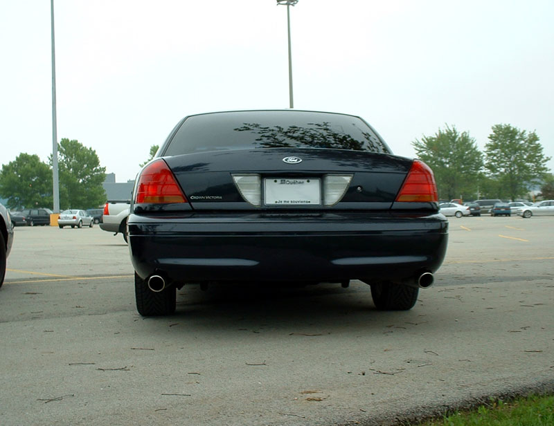 Dark blue 2000 Ford Crown Victoria rear view in a parking lot. Other cars and trees visible