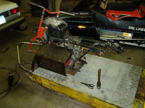 2000 Ford E350 - A partially disassembled snowmobile sits on a metal platform in a garage. Tools like scissors and a hammer are on the platform next to the…