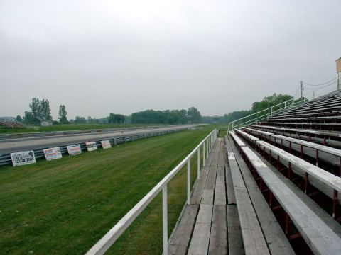 2000 Ford Crown Victoria - A view of a drag strip and empty bleachers on an overcast day. Signs are visible along the side of the track.
