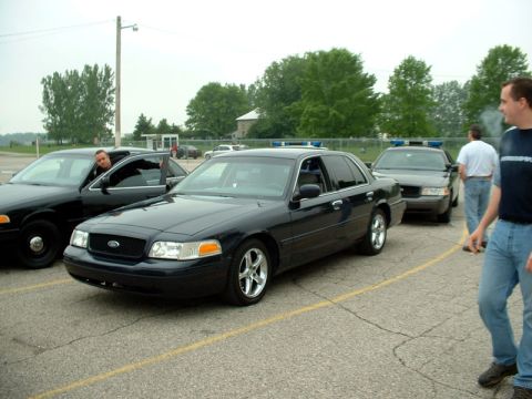 2000 Ford Crown Victoria - Several Ford Crown Victoria police sedans are parked together outdoors under an overcast sky.