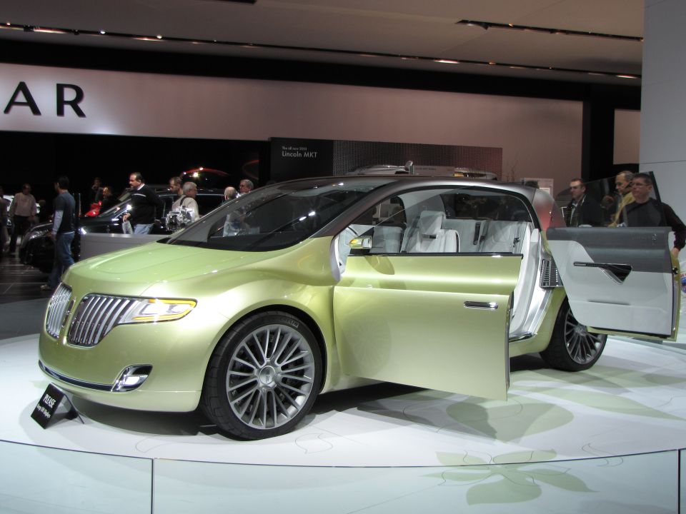 Light green Lincoln MKT concept car with doors open, showing white interior, on display.