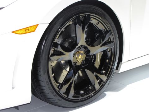 1996 Ford Probe - Close-up of the front passenger-side wheel and fender of a white car, likely a sports car, with a black multi-spoke alloy wheel featuring t…