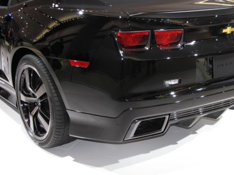 1996 Ford Probe - The rear passenger side of a black Chevrolet Camaro is shown, featuring its distinctive taillights, rear bumper with exhaust outlets, and a…