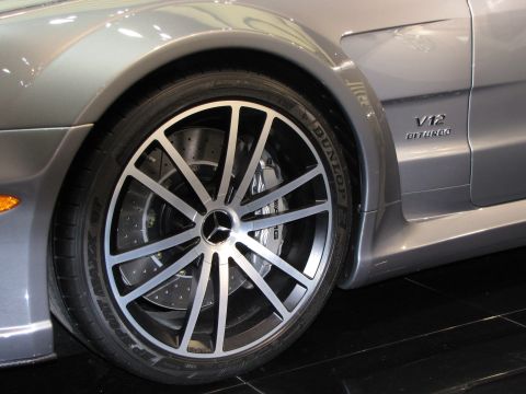1996 Ford Probe - Close-up of the front passenger side wheel and fender of a silver Mercedes-Benz, featuring a V12 Biturbo badge. The wheel is a multi-spoke…