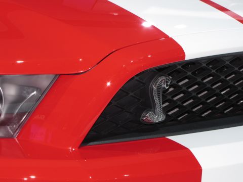 1996 Ford Probe - A close-up of the front grille of a red and white vehicle, featuring a silver cobra emblem.