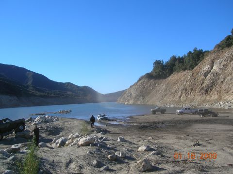 1985 Ford Bronco - A scenic view of a lake surrounded by rocky hills and vegetation under a bright blue sky.