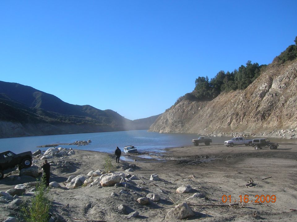 Lake and rocky shore with hills under a clear blue sky