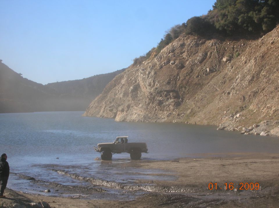 Off-road vehicle driving on a dusty dirt road with hills in the background