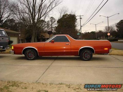 1971 Ford Ranchero - Side view of an orange 1971 Ford Ranchero parked on a street with trees in the background.