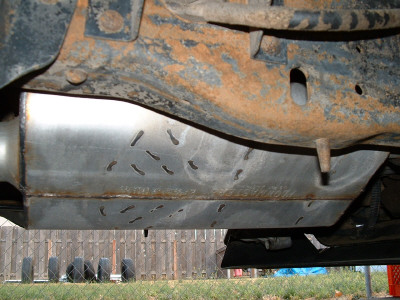 1991 Ford Bronco - Undercarriage view of a vehicle's frame and skid plate, showing rust and perforations.