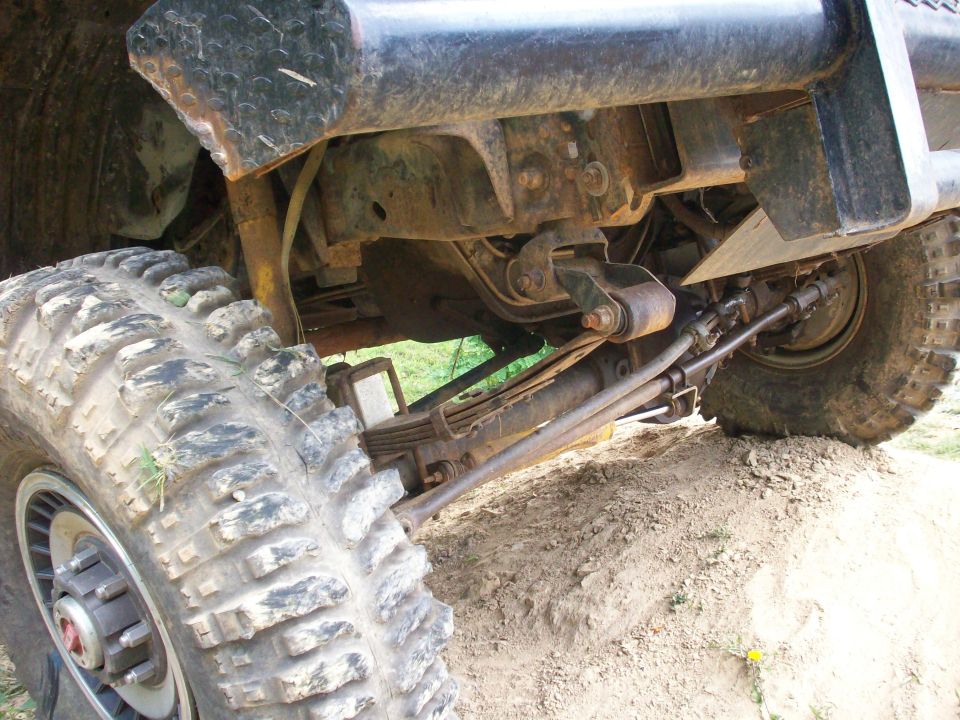 Close-up of off-road vehicle front tire, suspension, and steering components.