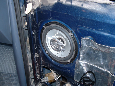 1991 Ford Bronco - Close-up of a car door interior revealing a speaker installation with visible wiring and insulation material.