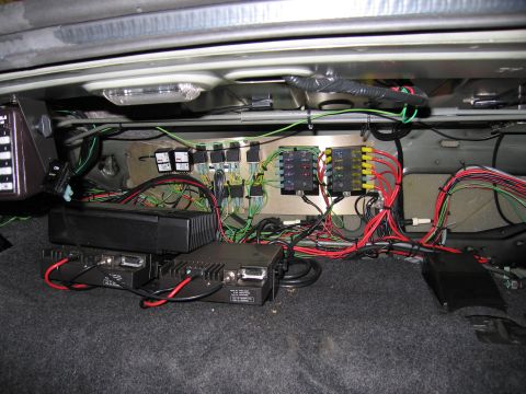 1991 Ford LTD Crown Victoria - Photograph of relays, fuses and electronic equipment wired into a vehicle trunk, not a technical diagram.