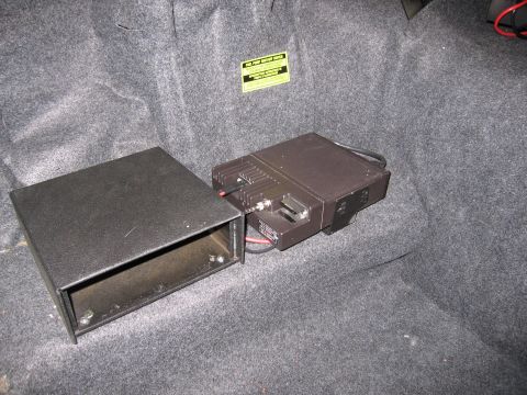 1991 Ford LTD Crown Victoria - Photograph of electronic equipment in a vehicle trunk with a warning label, not a technical document.