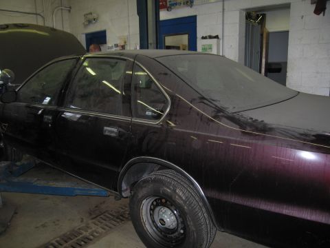 1991 Ford LTD Crown Victoria - A dusty dark purple sedan sits in a garage with its hood up.
