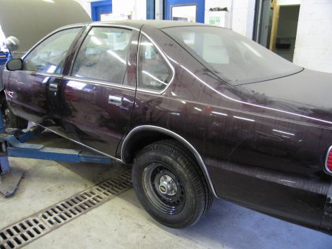 1991 Ford LTD Crown Victoria - Side view of a dark sedan on a car lift, hood is open, interior is dusty.