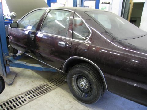 1991 Ford LTD Crown Victoria - A dark red 1991 Ford Crown Victoria LTD is raised on a car lift inside a garage.