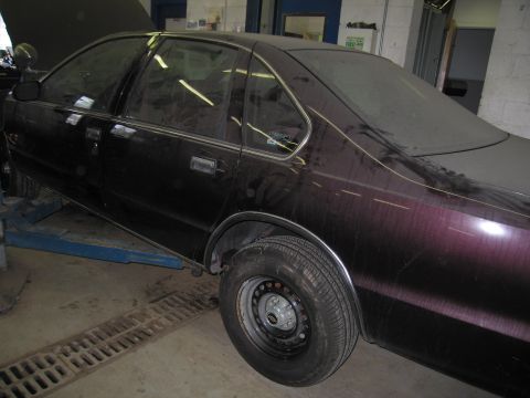 1991 Ford LTD Crown Victoria - A 1991 Ford Crown Victoria LTD, appearing to be in storage or undergoing maintenance, is shown from the side on a lift.