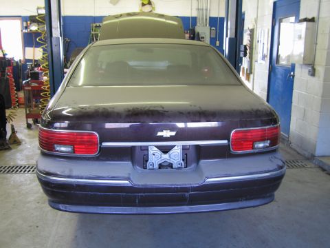 1991 Ford LTD Crown Victoria - Rear view of a dusty maroon Chevrolet Caprice in a garage, showing its taillights and license plate area.