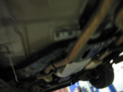 1991 Ford LTD Crown Victoria - The underside of a vehicle is visible, with focus on the exhaust system and suspension parts.