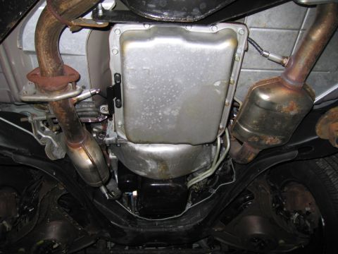 1991 Ford LTD Crown Victoria - The undercarriage of a car reveals its transmission, exhaust system, and catalytic converter, showing signs of age.