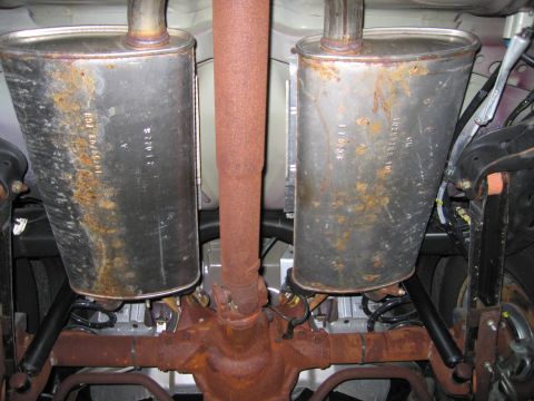 1991 Ford LTD Crown Victoria - Rear axle and dual exhaust mufflers on a car, showing significant rust and stamped part numbers.