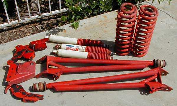Red-painted suspension parts: coil springs, Rancho shocks, and brackets on concrete