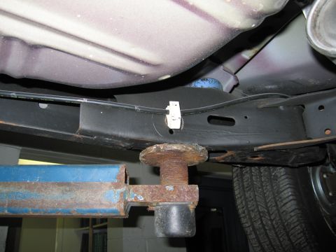 1991 Ford LTD Crown Victoria - Underside view of a vehicle supported by a car lift, showing frame and brake lines.