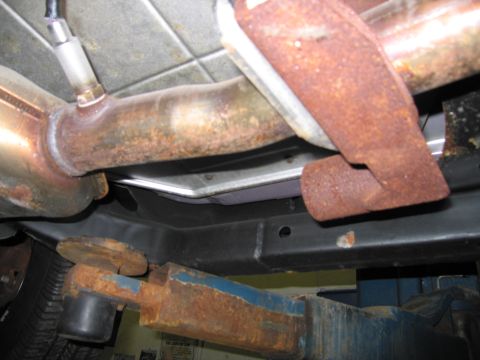 1991 Ford LTD Crown Victoria - The underside of a vehicle shows a rusty exhaust system, including the muffler and pipes, supported by a lift.