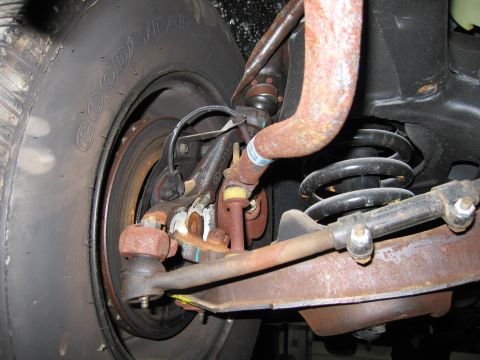 1991 Ford LTD Crown Victoria - Close-up of rusty car suspension parts, including a tire, coil spring, and tie rod, with no visible year identification.