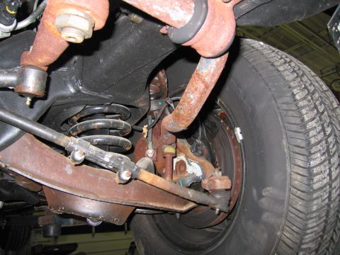 1991 Ford LTD Crown Victoria - Close-up view of the suspension system and tire from underneath a vehicle.
