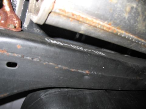 1991 Ford LTD Crown Victoria - Close-up of a vehicle's undercarriage part, showing stamped text and signs of rust.
