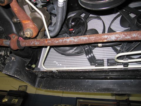 1991 Ford LTD Crown Victoria - Underside view of a vehicle's front end, showing a rusty sway bar and radiator assembly.