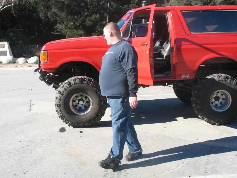 Red 1987 Ford Bronco with lifted suspension and off-road tires