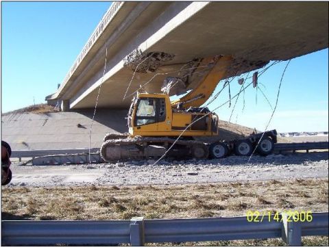 1995 Ford Bronco - An excavator is positioned under a damaged concrete overpass, with debris visible. The date 02/14/2006 is stamped on the image.