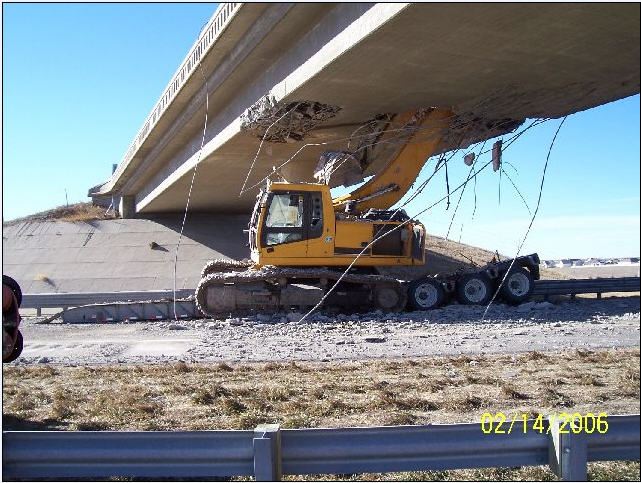 Yellow excavator beneath damaged overpass, 02/14/2006