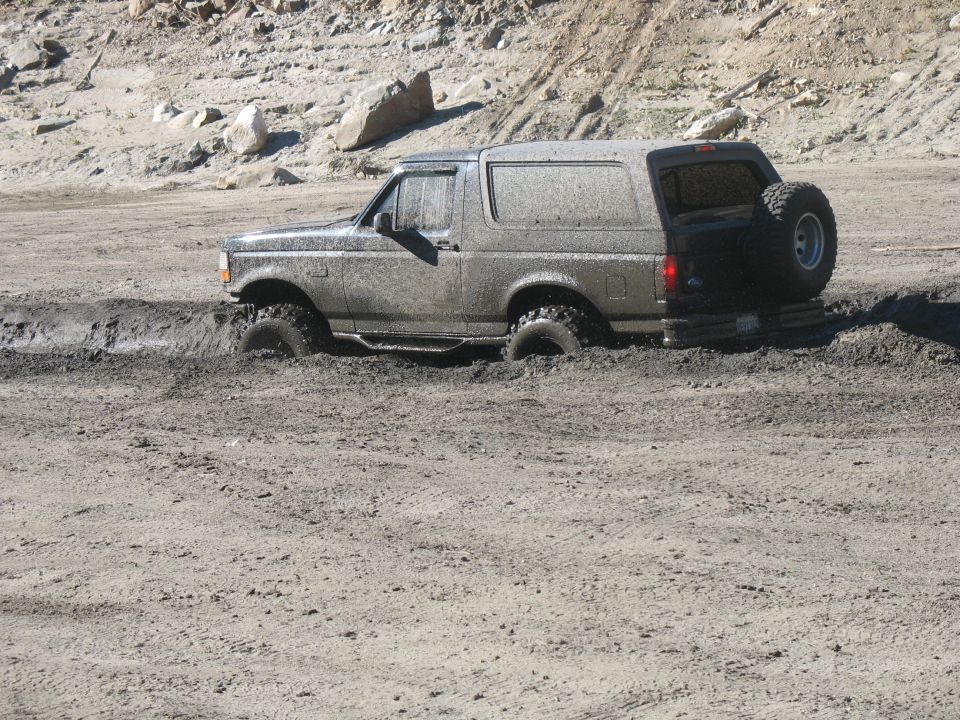 Mud-covered SUV stuck in mud with spare tire on back