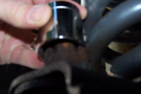 1990 Ford Bronco - A hand is holding a chrome-plated component, possibly a cap or adapter, over a dark, textured surface that appears to be part of a vehicle'…